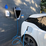 uma parede com uma conexão elétrica ligada a um carro recarregando